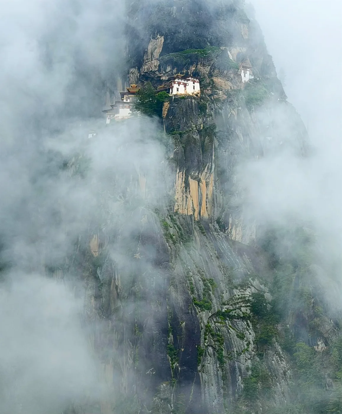 A remote monastery emerging through mountain mist
