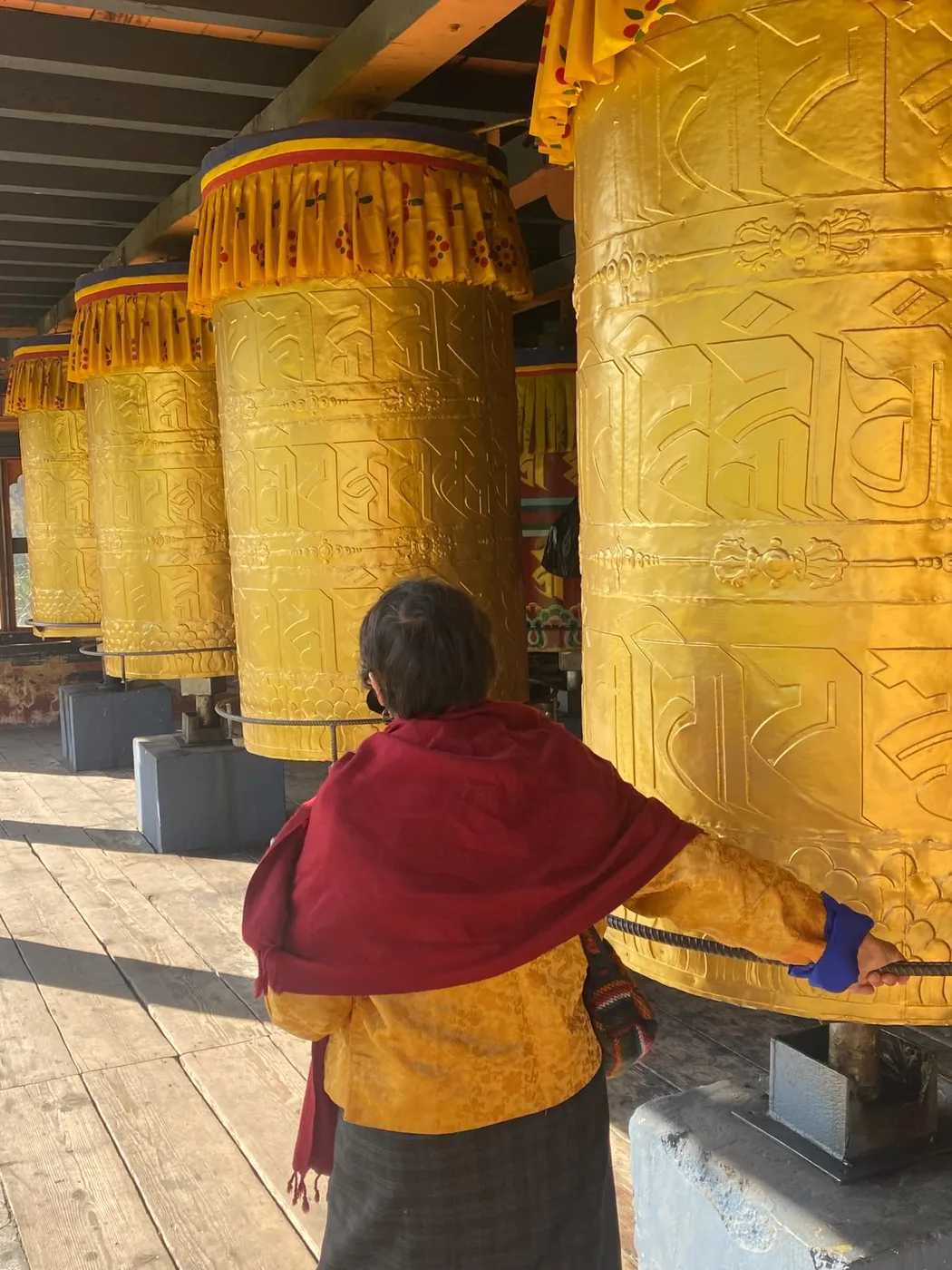 A monk walking beside golden prayer wheels in Bhutan
